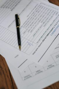 A detailed view of graded test papers with a pen resting on a wooden desk.